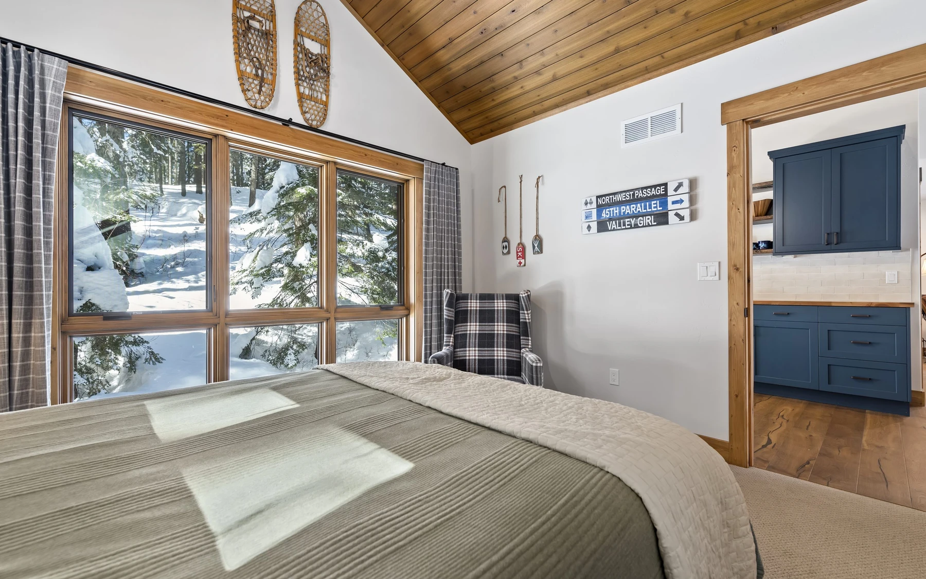 Bedroom in the Plymouth Retreat mountain home near McCall, with a layered bed, large windows, and wood details.