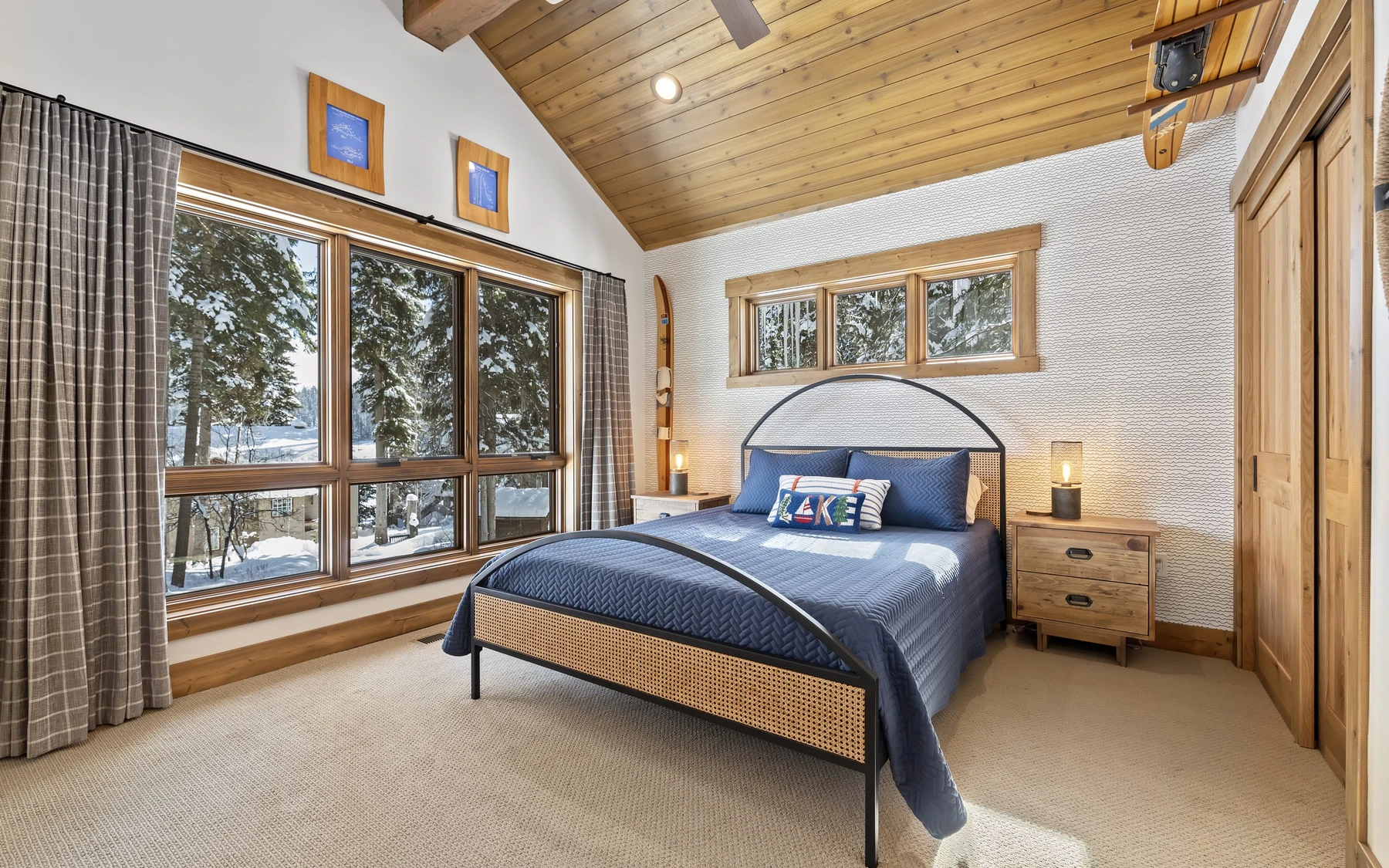 Bedroom in the Plymouth Retreat mountain home near McCall, with a layered bed, large windows, and wood details.