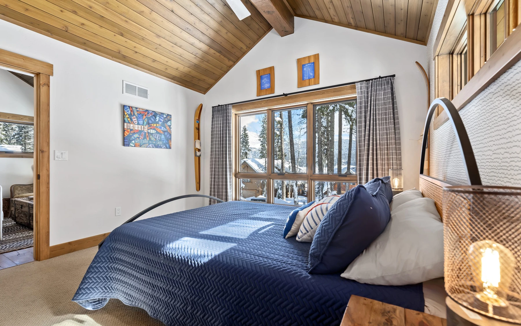 Bedroom in the Plymouth Retreat mountain home near McCall, with a layered bed, large windows, and wood details.