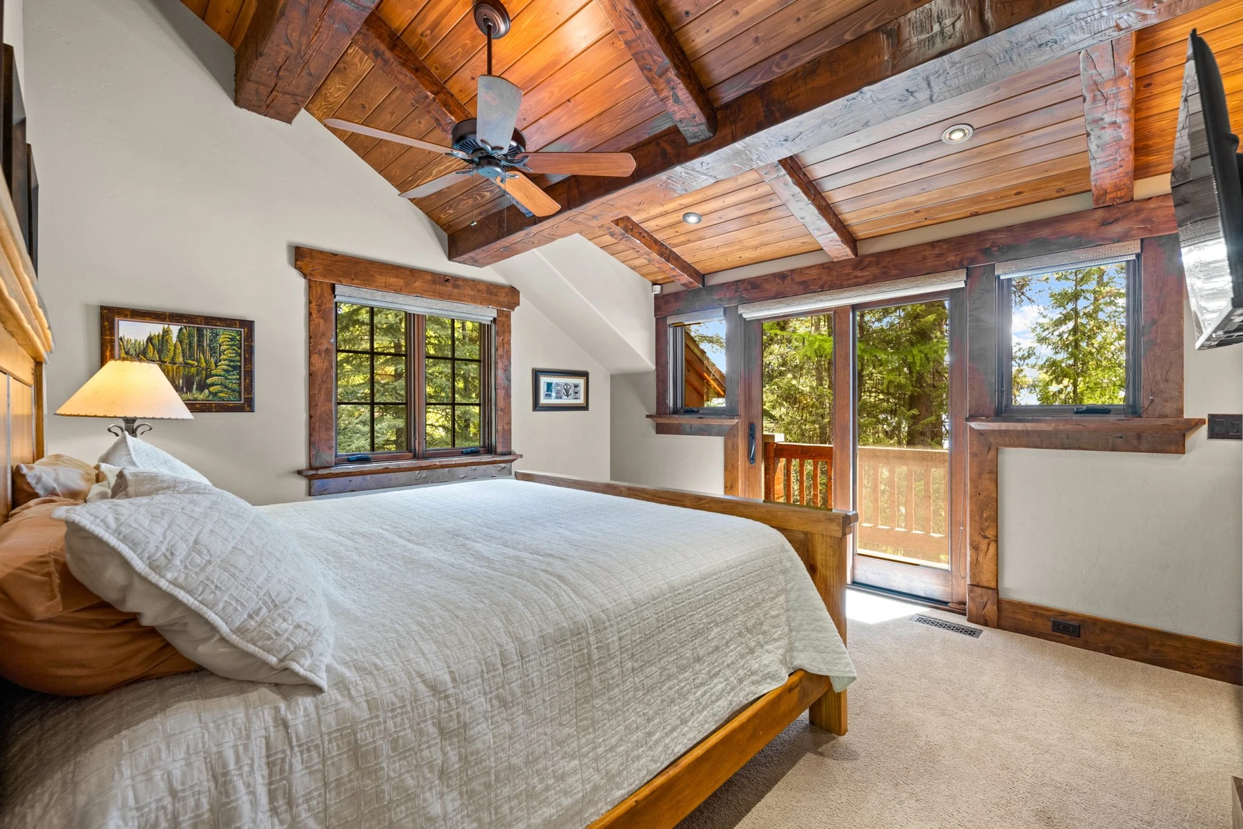 Bedroom in the Rocky Shore lakefront home on Payette Lake, with a layered bed, large windows, and wood details.