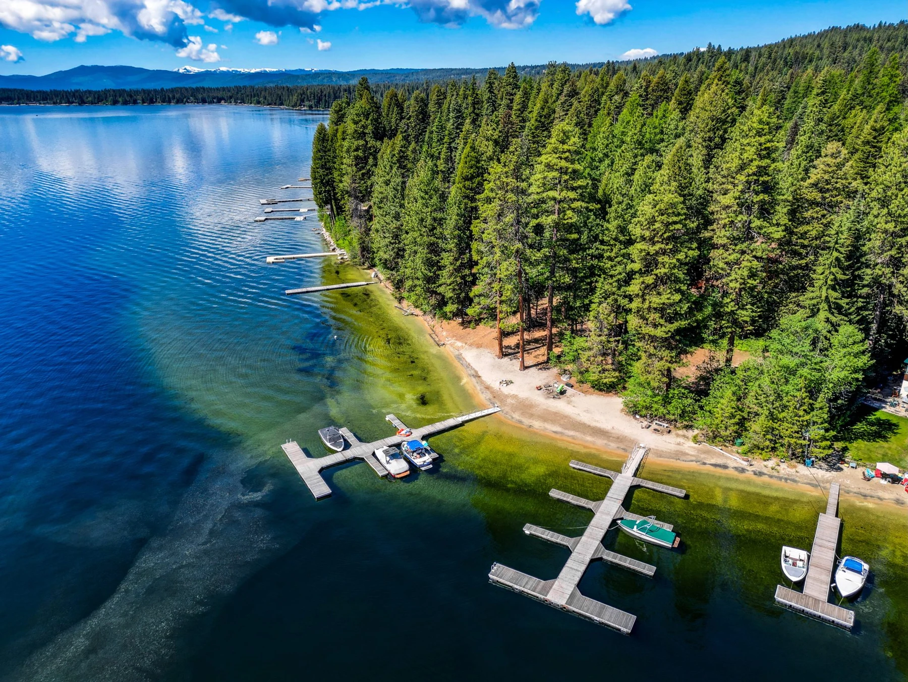 Aerial view of the Rocky Shore lakefront home on Payette Lake, showing the lake shoreline, the surrounding forest, and the mountain setting.