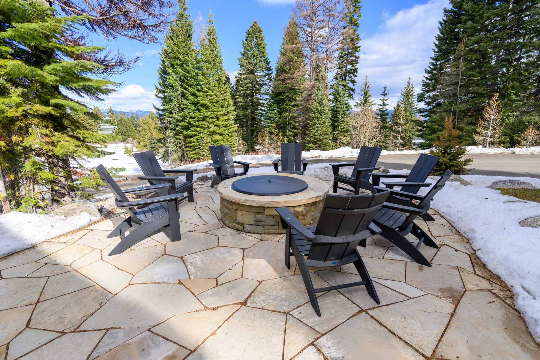 Covered outdoor space at the SlopeSide Escape ski home at Tamarack Resort, with outdoor seating, forest views, and a winter setting.
