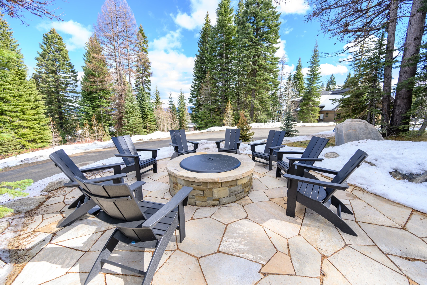 Covered outdoor space at the SlopeSide Escape ski home at Tamarack Resort, with outdoor seating, timber details, and forest views.