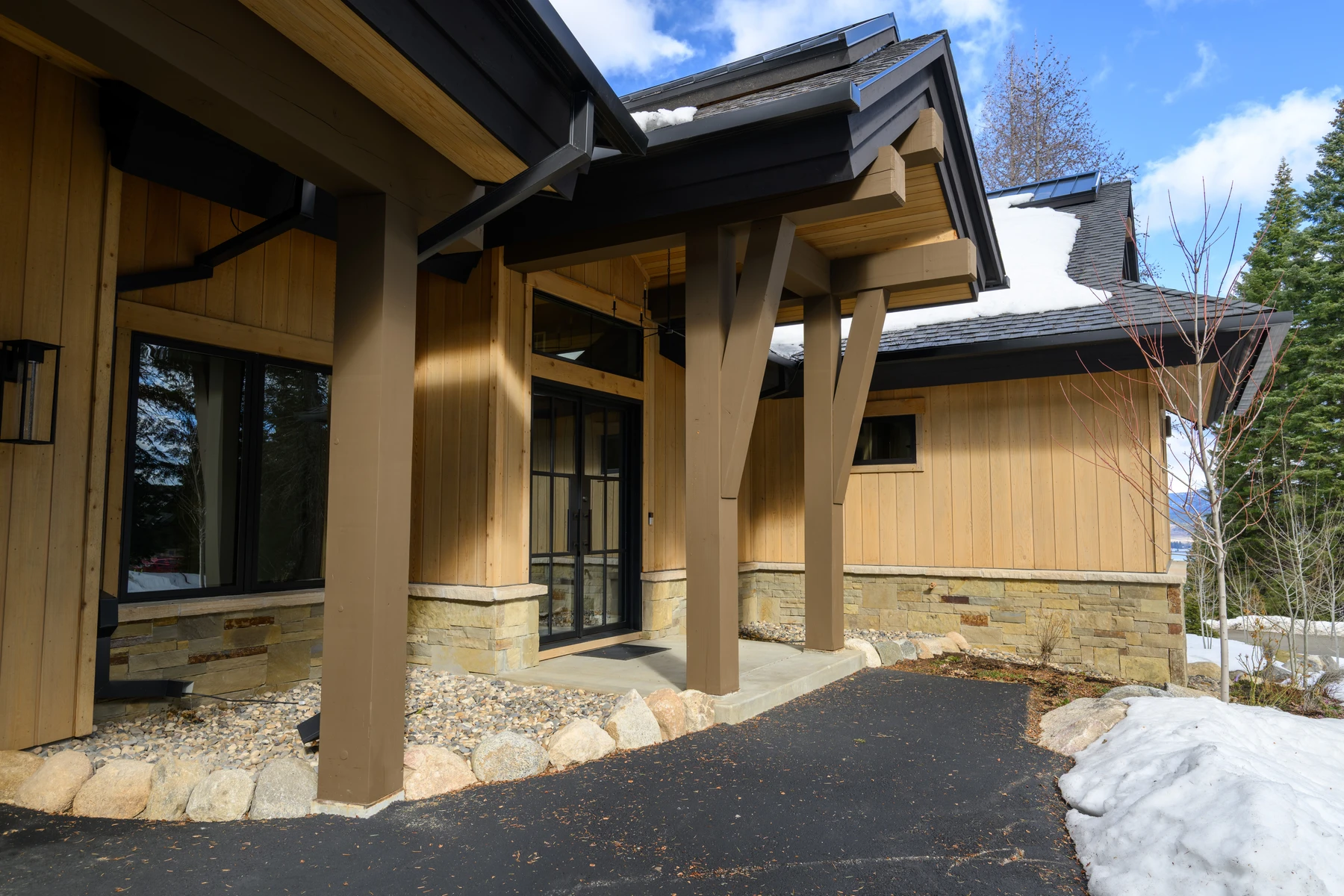 Exterior of the SlopeSide Escape ski home at Tamarack Resort, showing wood siding and timber details, stonework, and large windows.