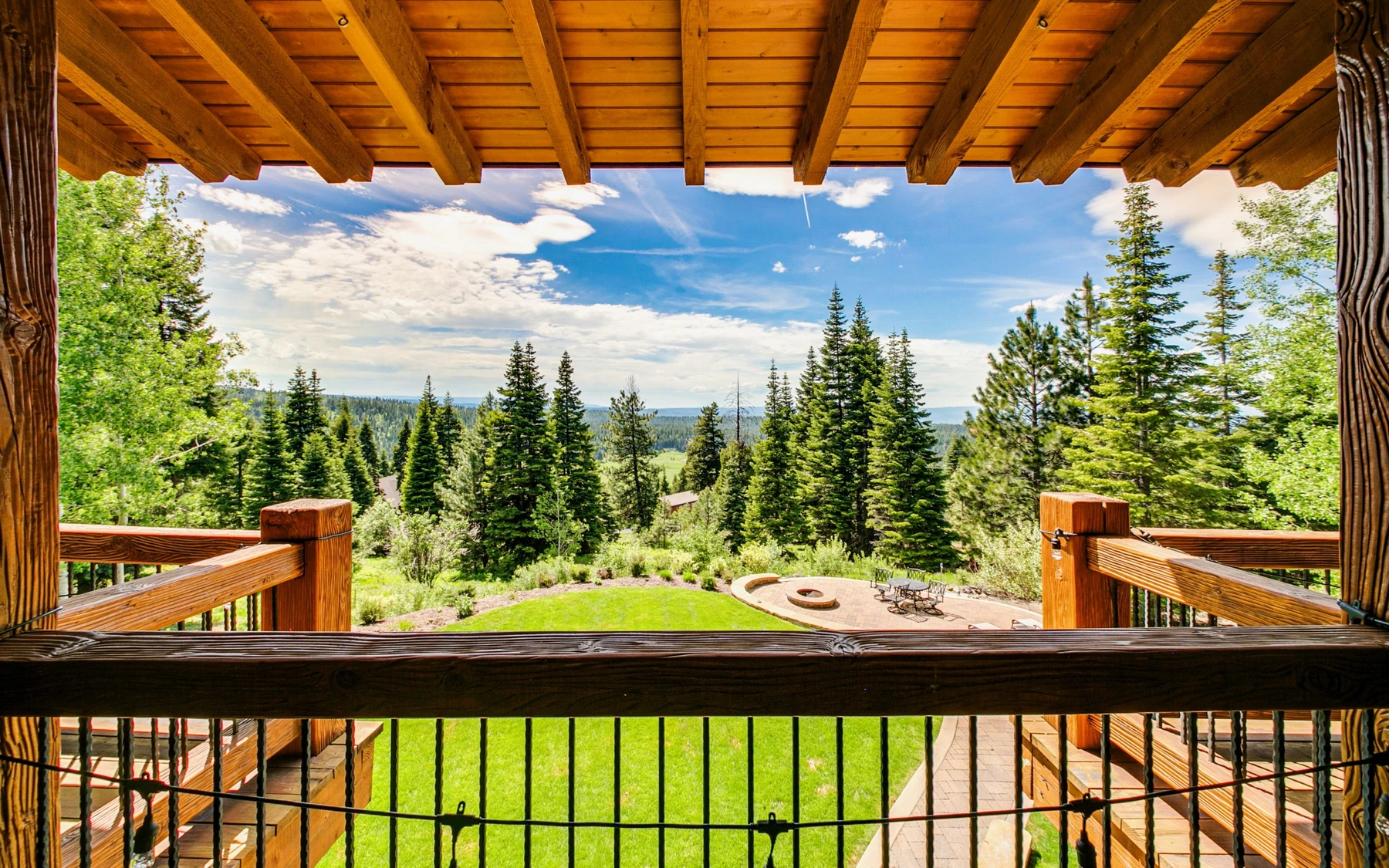 Covered outdoor space at the Summit Sanctuary ridgeline home near McCall, with outdoor seating, timber details, and forest views.