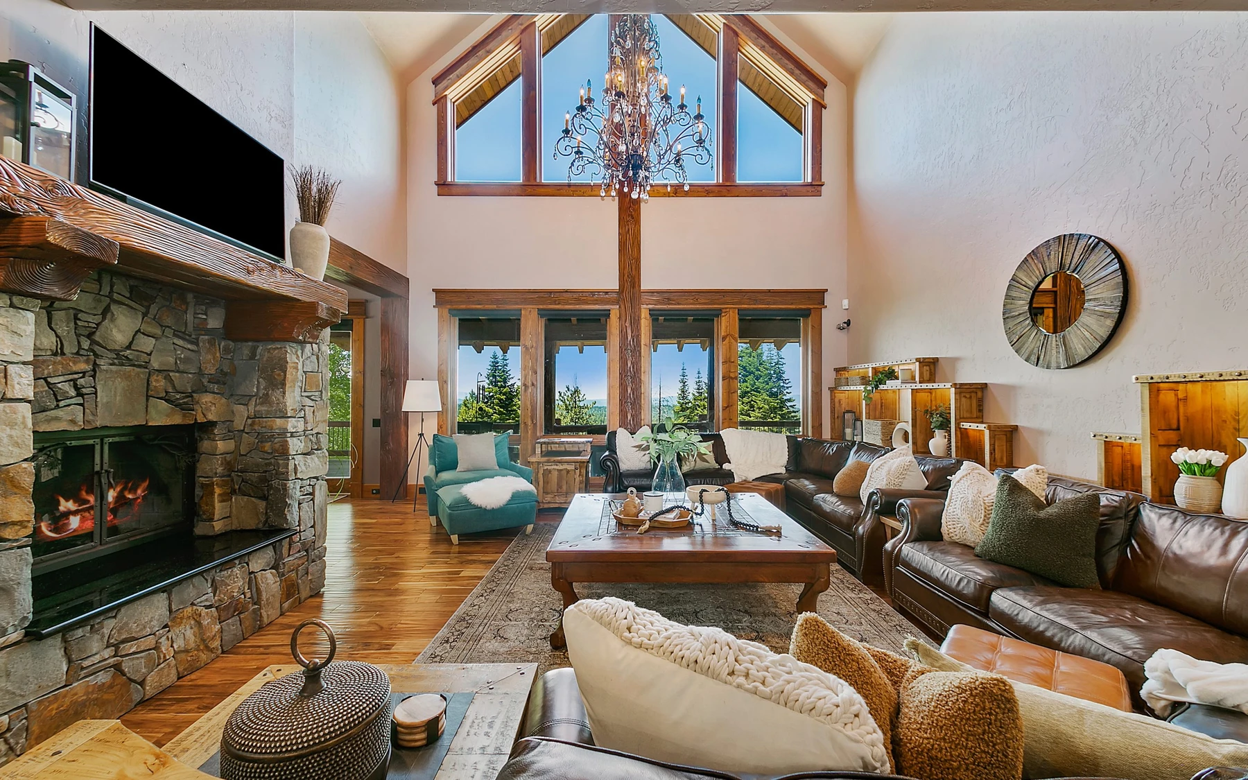 Living room in the Summit Sanctuary ridgeline home near McCall, with a fireplace, a relaxed seating area, and large windows.