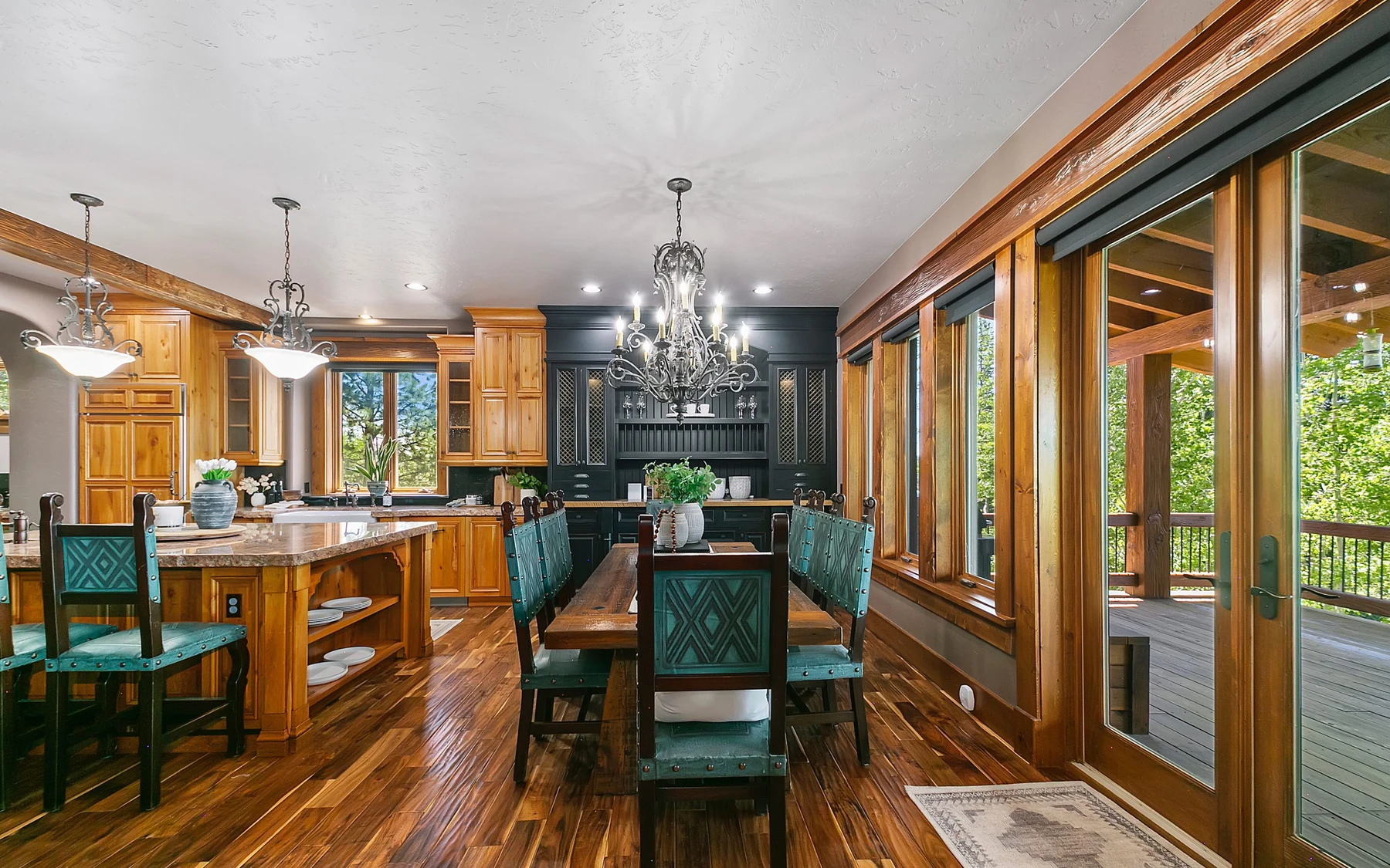 Dining room in the Summit Sanctuary ridgeline home near McCall, with a dining table, statement lighting, and large windows.