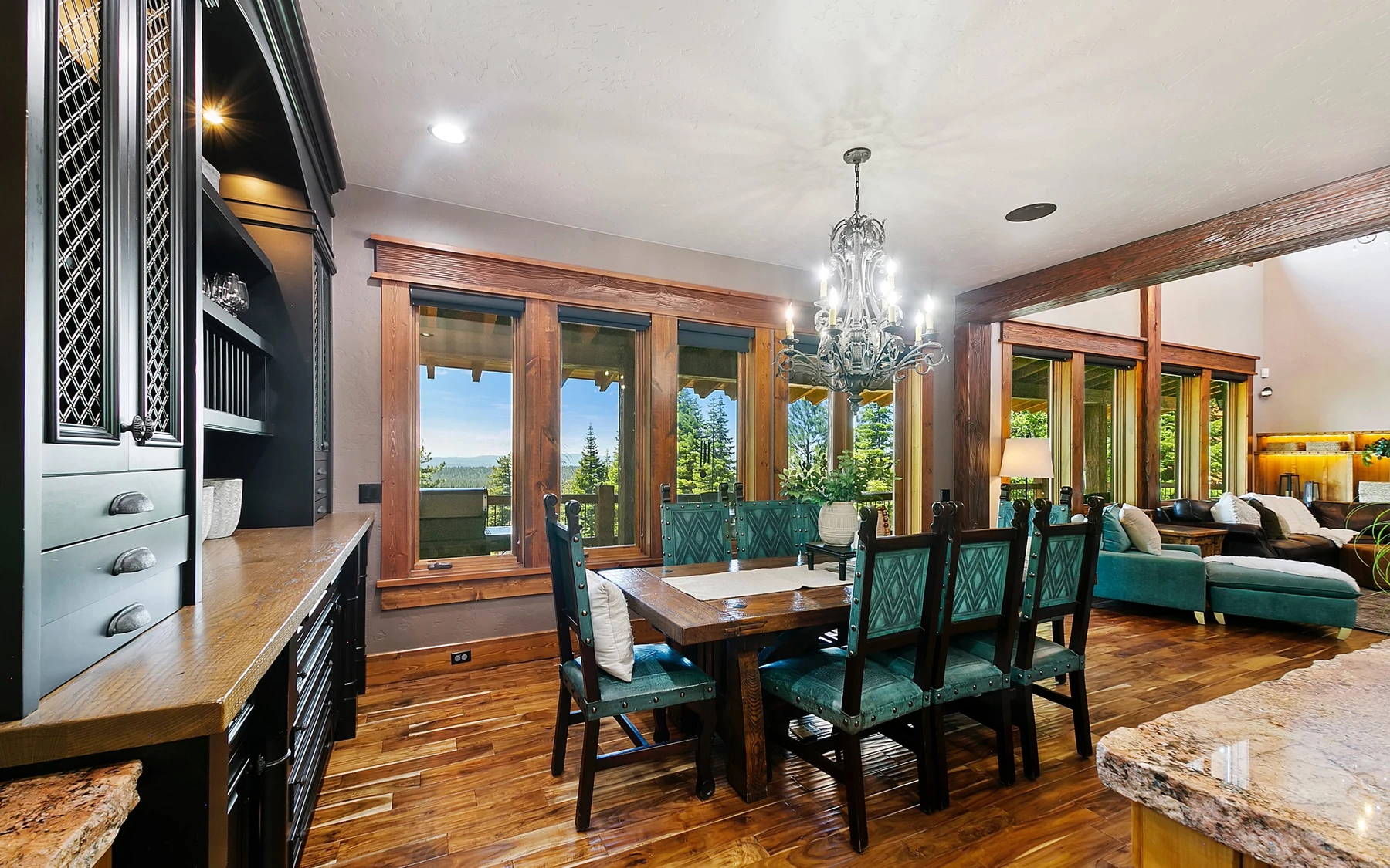 Dining room in the Summit Sanctuary ridgeline home near McCall, with a dining table, statement lighting, and large windows.