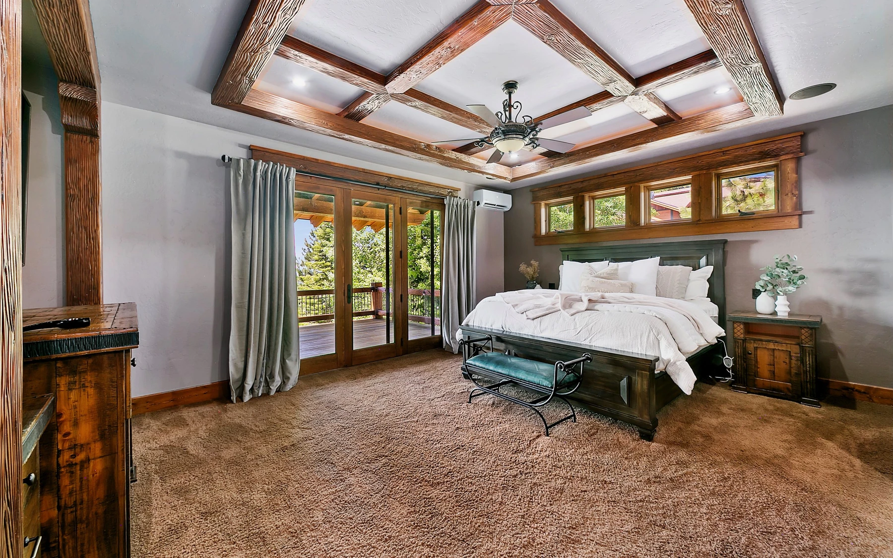 Bedroom in the Summit Sanctuary ridgeline home near McCall, with a layered bed, large windows, and wood details.